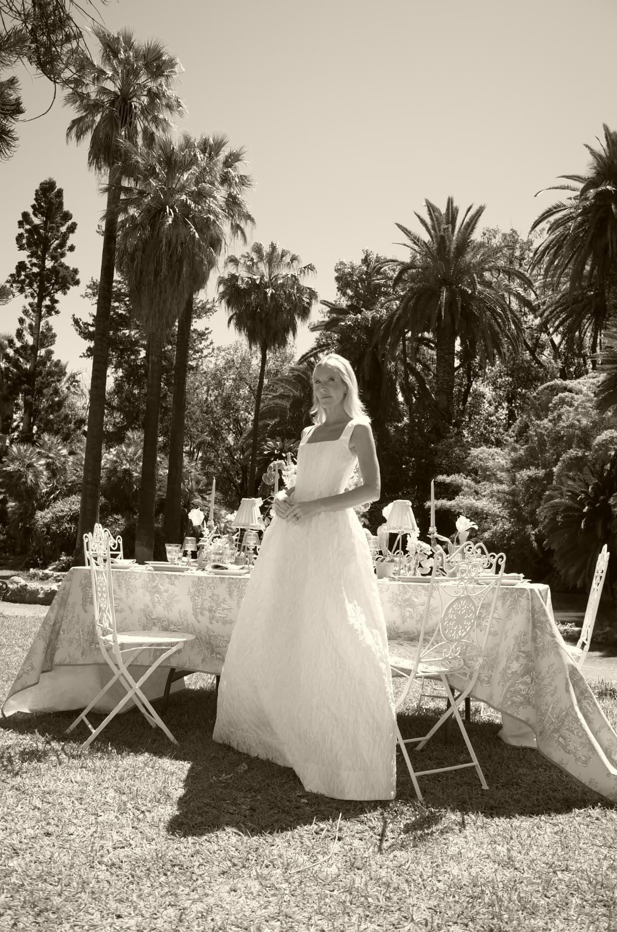 Woman in a white gown beside a garden table in Palermo